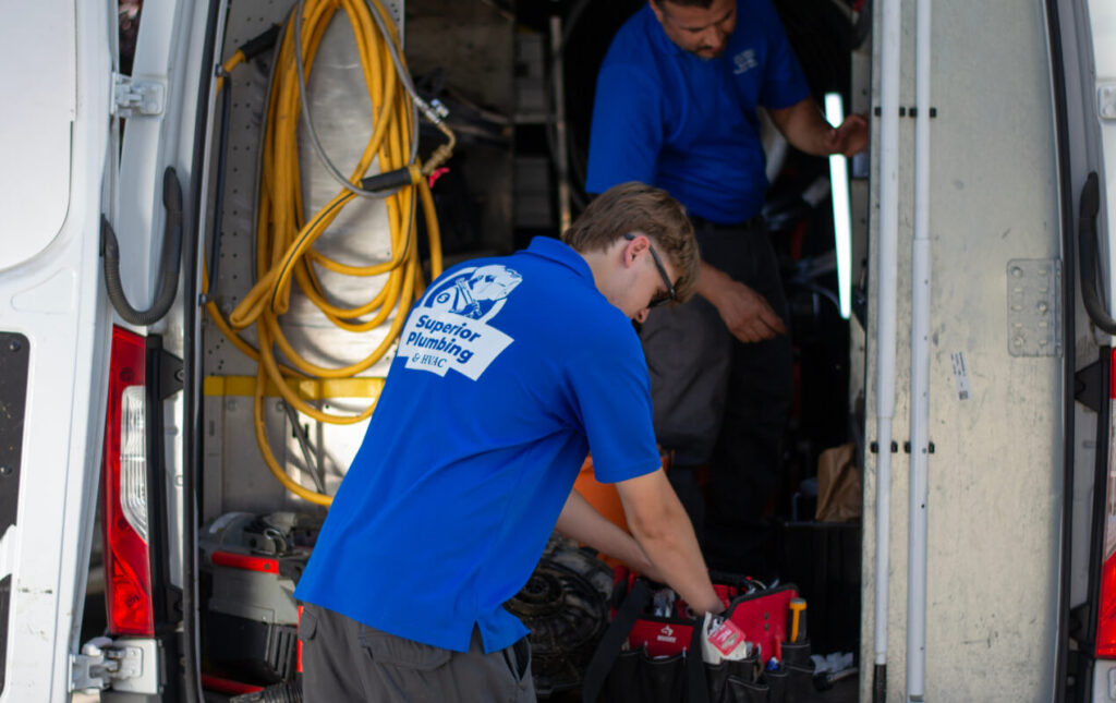 Superior Plumbing & Heating experts preparing for Drain Snaking by organizing tools in a professional service van