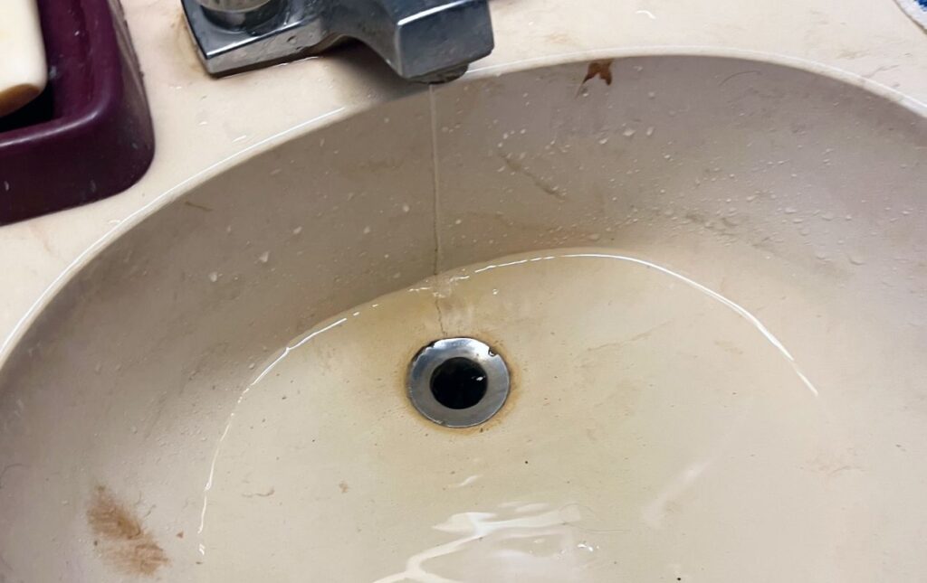 Superior Plumbing & Heating specialist working on a Drain Cleaning local project in a cabinet.