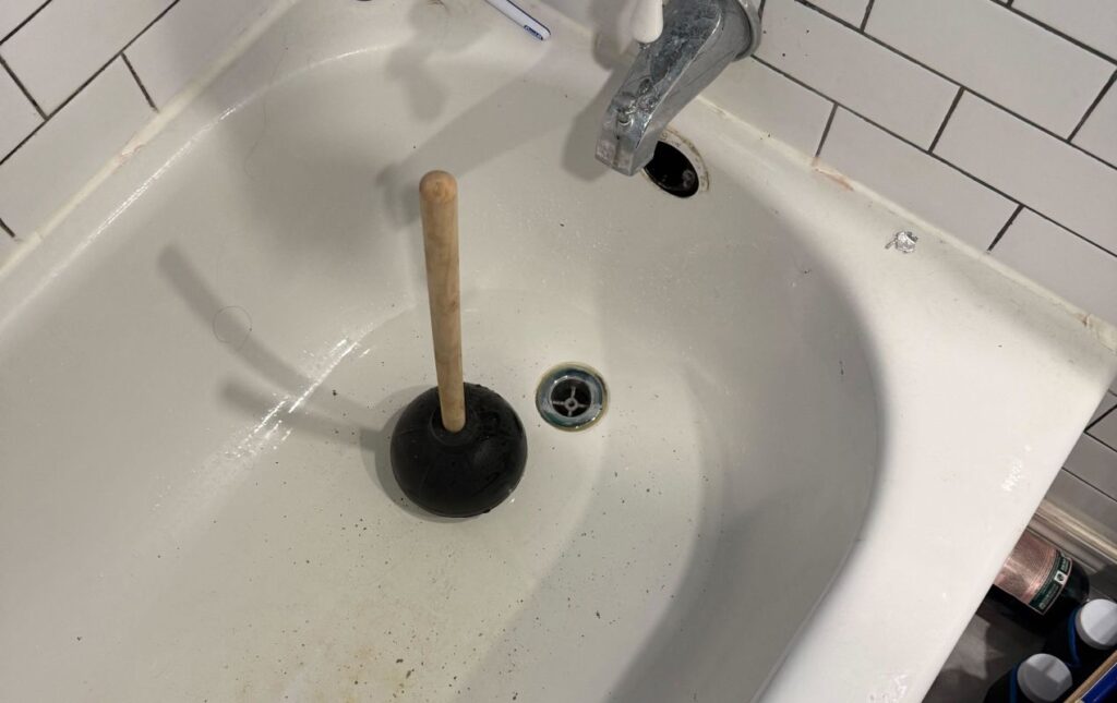 Superior Plumbing & Heating technician performing Drain Cleaning local under a kitchen sink.