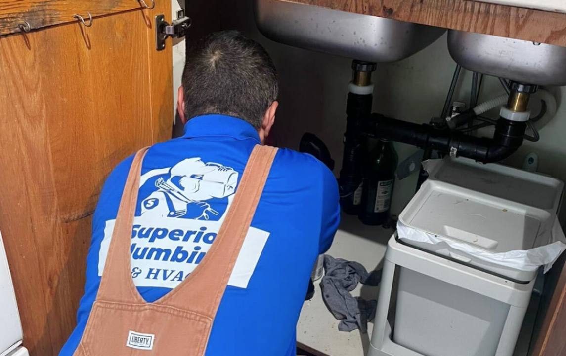 Superior Plumbing & Heating plumber working in a kitchen for a Drain Cleaning local task.