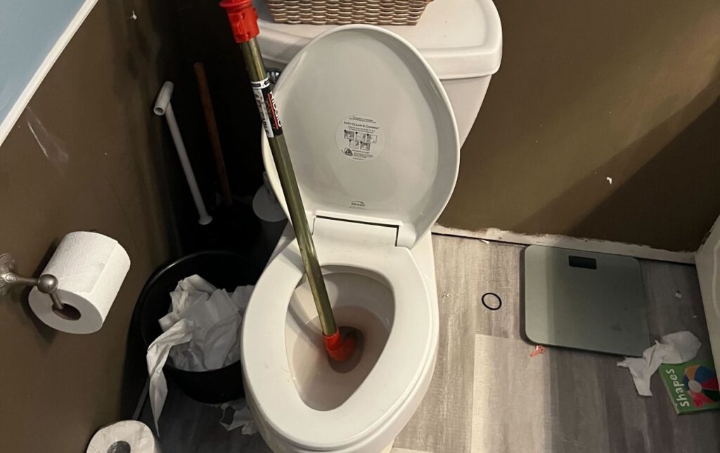 Clearing a toilet blockage during Drain Cleaning local by Superior Plumbing & Heating.