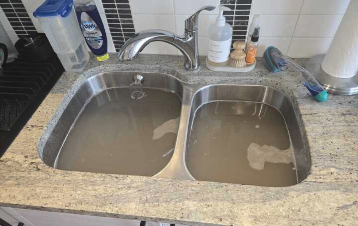 Kitchen sink full of wastewater needing Drain Cleaning local by Superior Plumbing & Heating.