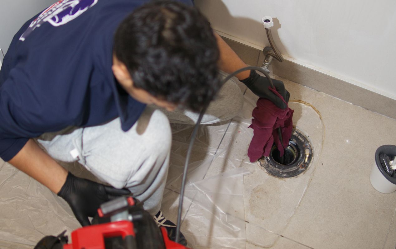 Superior Plumbing & Heating expert performing Drain Cleaning local on a floor drain.