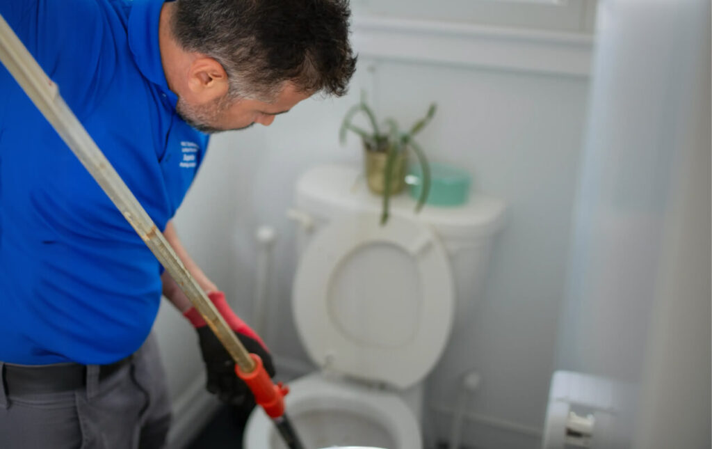 Superior Plumbing & Heating expert performing Drain Snaking to clear a toilet clog with a professional plumbing auger.
