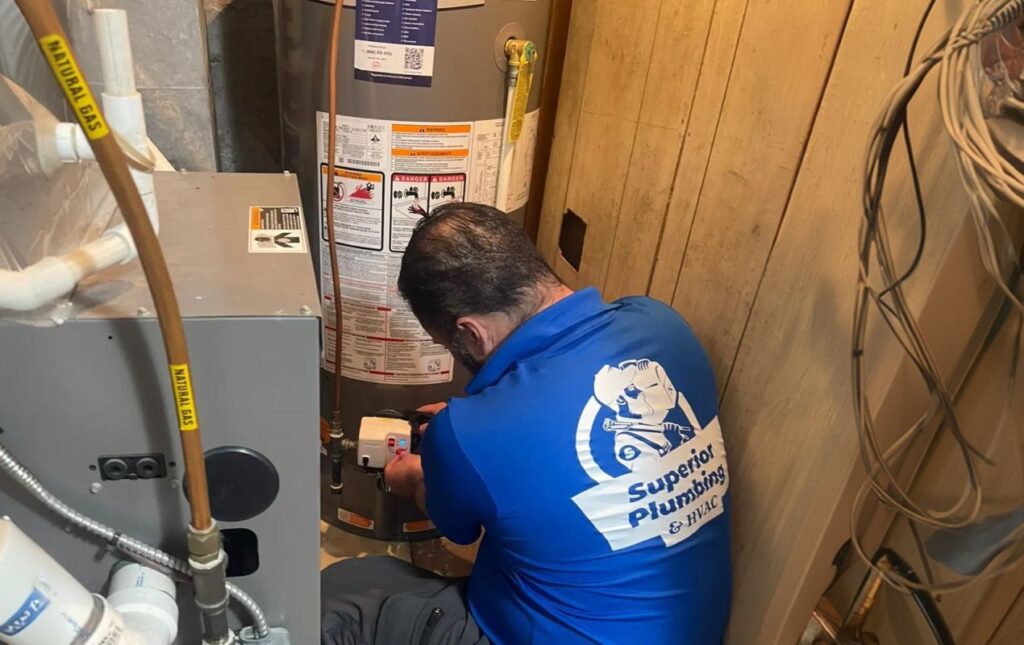 Superior Plumbing & Heating technician performing professional gas water heater installation and connection in a residential utility room