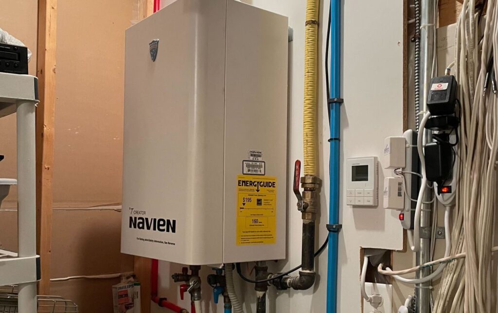 Superior Plumbing & Heating expert installing a Navien tankless water heater for high-efficiency on-demand hot water in a residential home