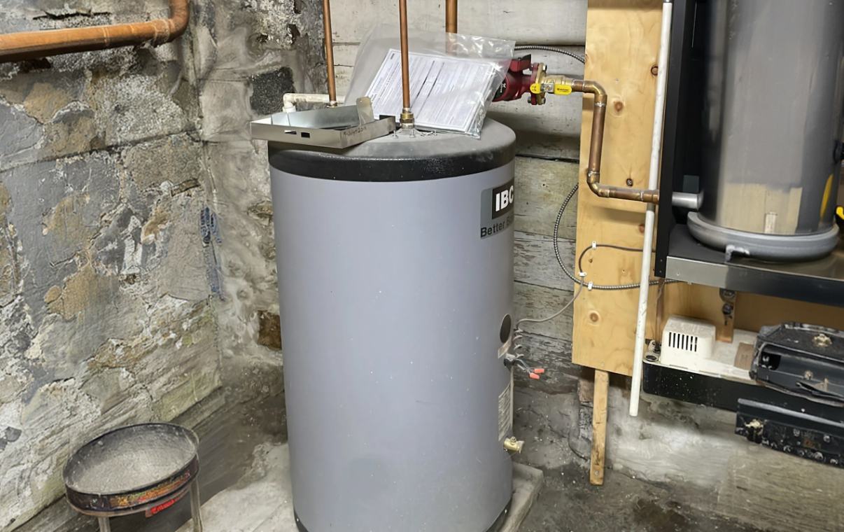 Superior Plumbing & Heating specialist installing a high-capacity residential water heater with reinforced plumbing connections in a basement