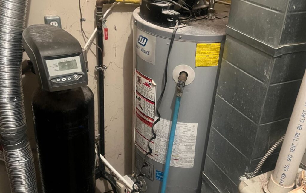 Superior Plumbing & Heating expert Water Softener Repair of a black media tank system next to a John Wood heater