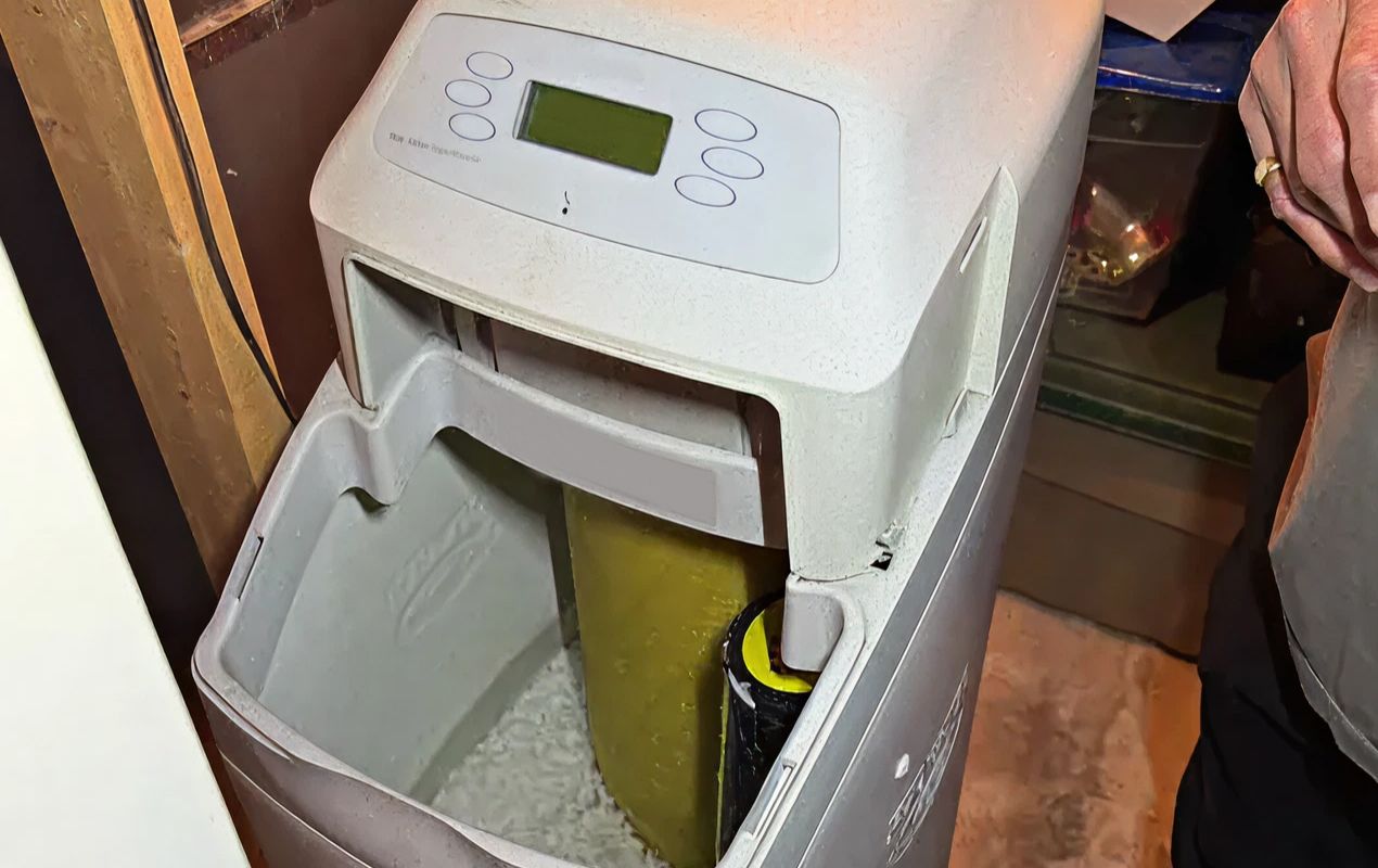 Superior Plumbing & Heating expert Water Softener Repair showing the internal salt reservoir of a white cabinet unit