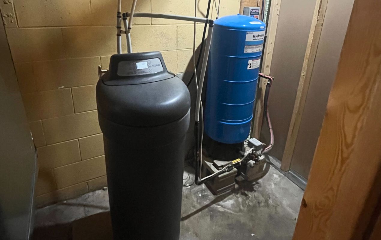 Superior Plumbing & Heating expert Water Softener Repair of a black cabinet unit next to a blue pressure tank