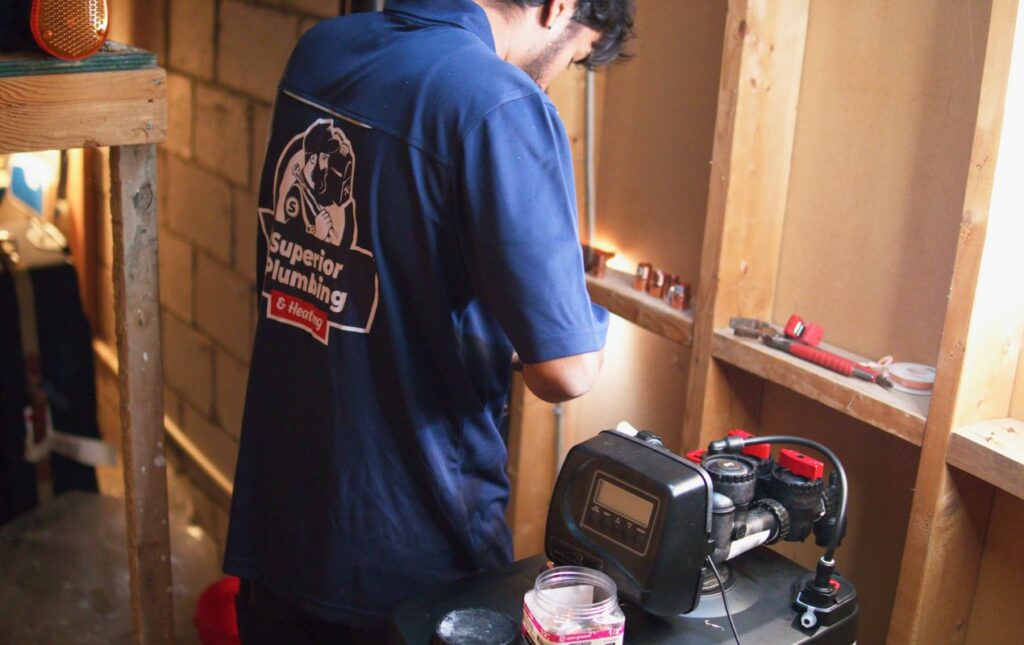 Superior Plumbing & Heating expert Water Softener Repair showing a technician working on a digital control head in a utility area