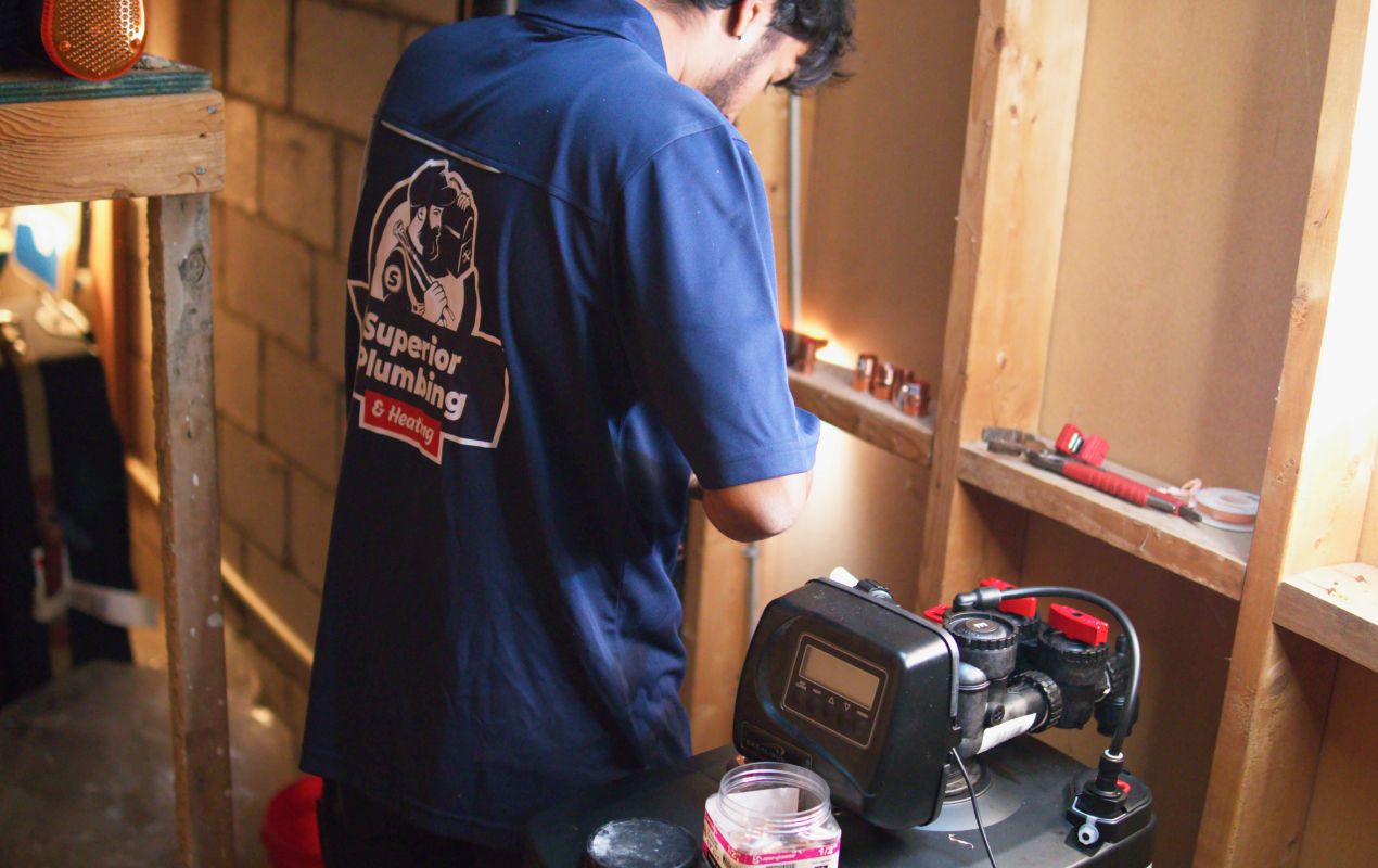 Superior Plumbing & Heating expert Water Softener Repair showing a technician working on a digital control head in a utility area