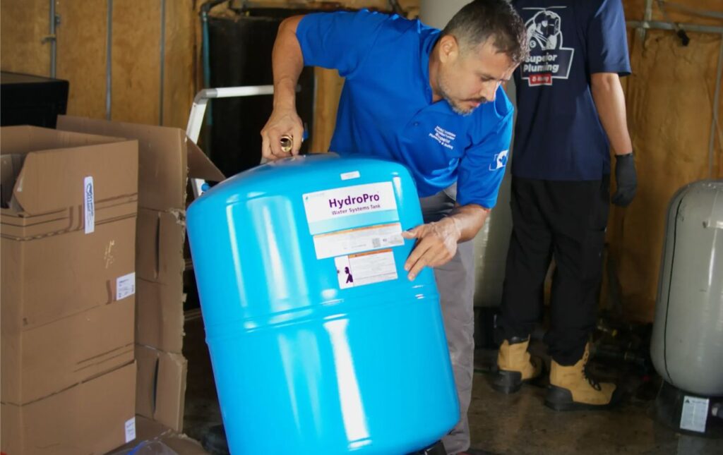 Professional from Superior Plumbing & Heating positioning a water system tank as part of a well pump installation local