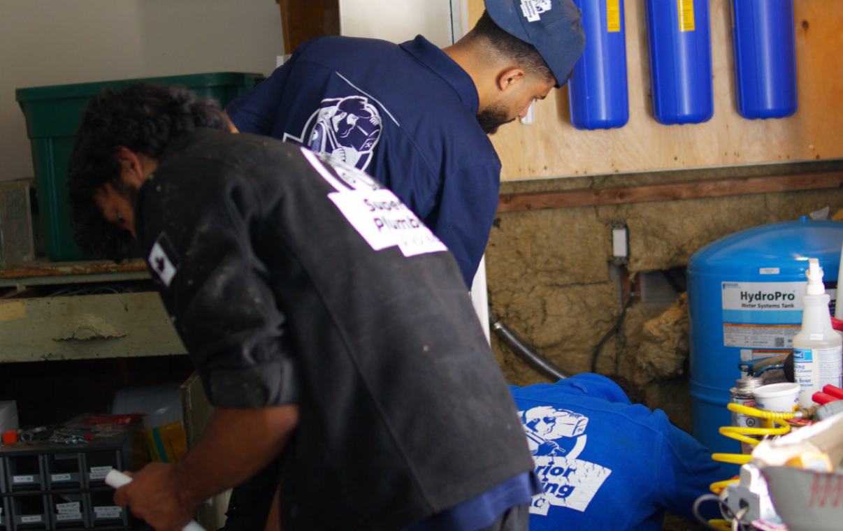 Two skilled plumbers from Superior Plumbing & Heating working on the piping for a well pump installation local