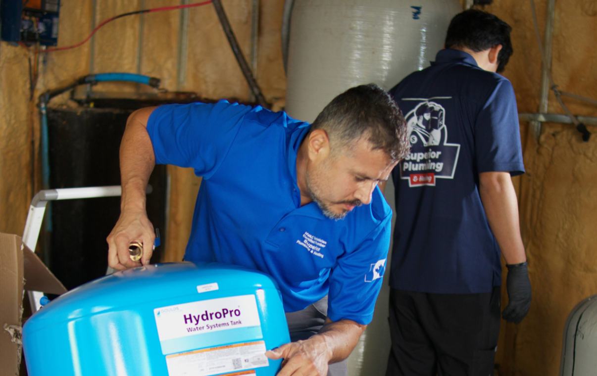 Superior Plumbing & Heating technician carefully moving a blue HydroPro tank for a well pump installation local
