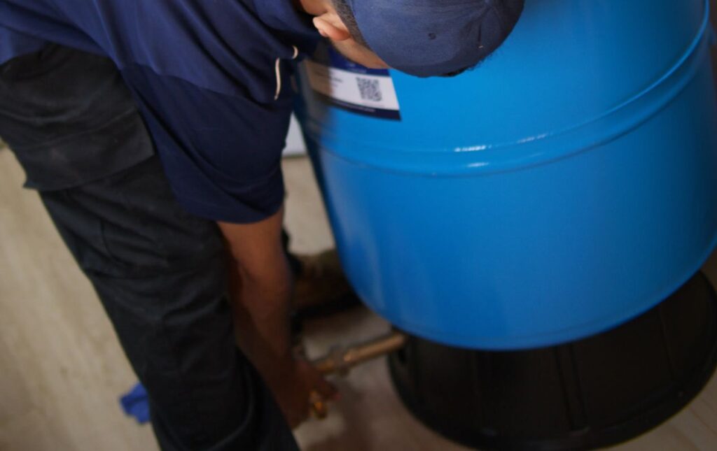 Detailed view of a technician from Superior Plumbing & Heating connecting pipes for a well pump installation local
