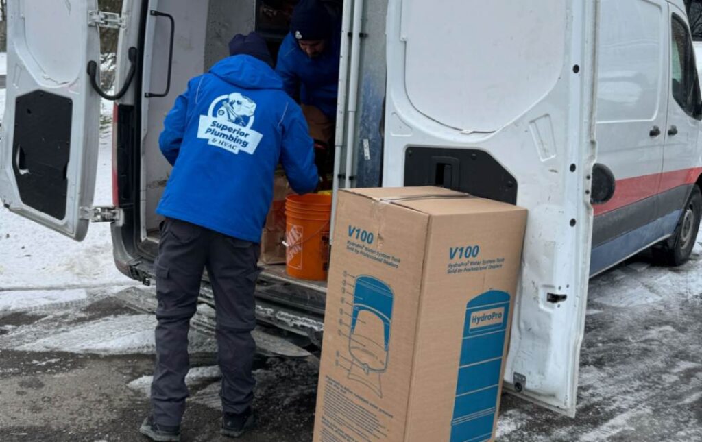 Superior Plumbing & Heating technicians unloading new equipment for a well pump installation local from a service van