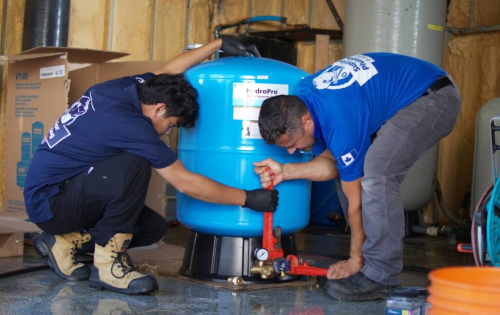 Superior Plumbing & Heating techs using a wrench for Well pump installation on a HydroPro water tank