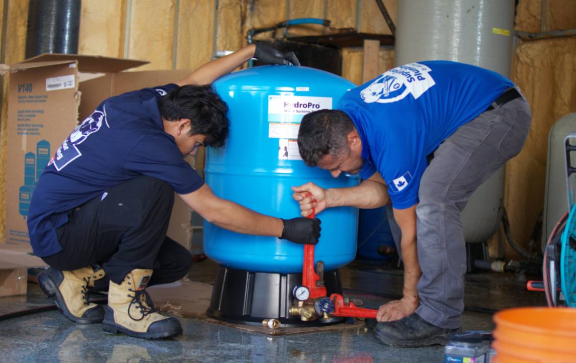 Superior Plumbing & Heating techs using a wrench for Well pump installation on a HydroPro water tank