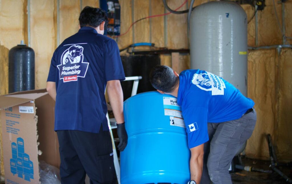 Superior Plumbing & Heating techs positioning a blue tank for Well pump installation