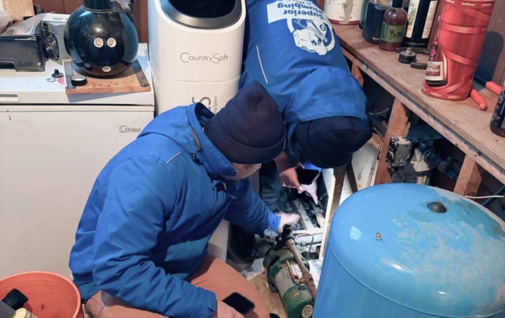 Techs performing Well pump repair local by Superior Plumbing & Heating in basement.
