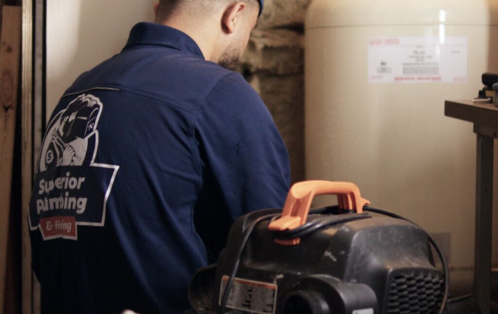 Licensed specialist from Superior Plumbing & Heating working on a well pump replacement local in a basement